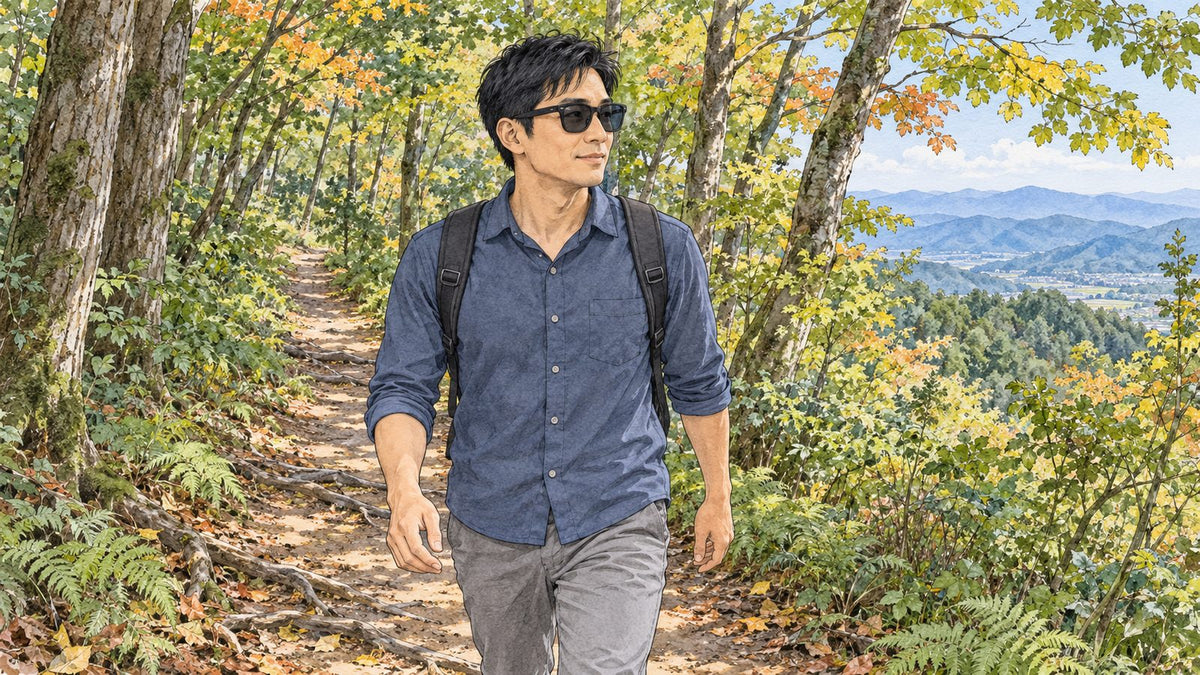 紅葉が始まった樹林帯の登山道を歩くサングラス姿の男性
